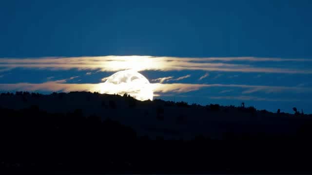 Full moon illuminating mountains under cloudy sky AI video preview