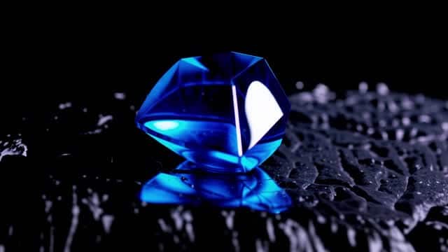 Blue brilliant gemstone placed on rough dark texture AI video preview
