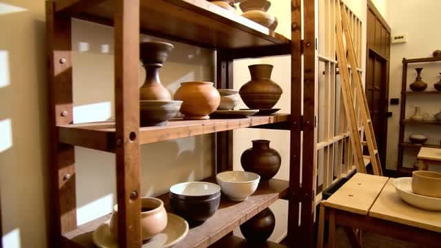 Display of artisan pottery and ceramic vessels on wood shelf AI video preview