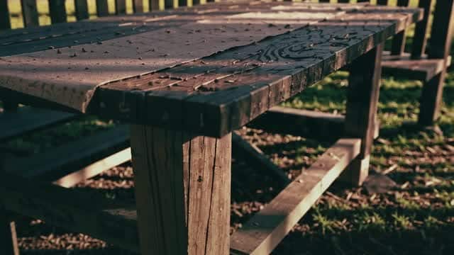 Weathered wooden outdoor picnic table on grass AI video preview