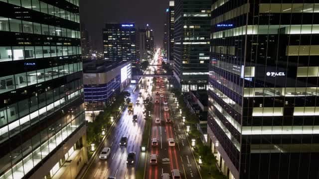 Busy nighttime cityscape traffic passing between modern towers AI video preview